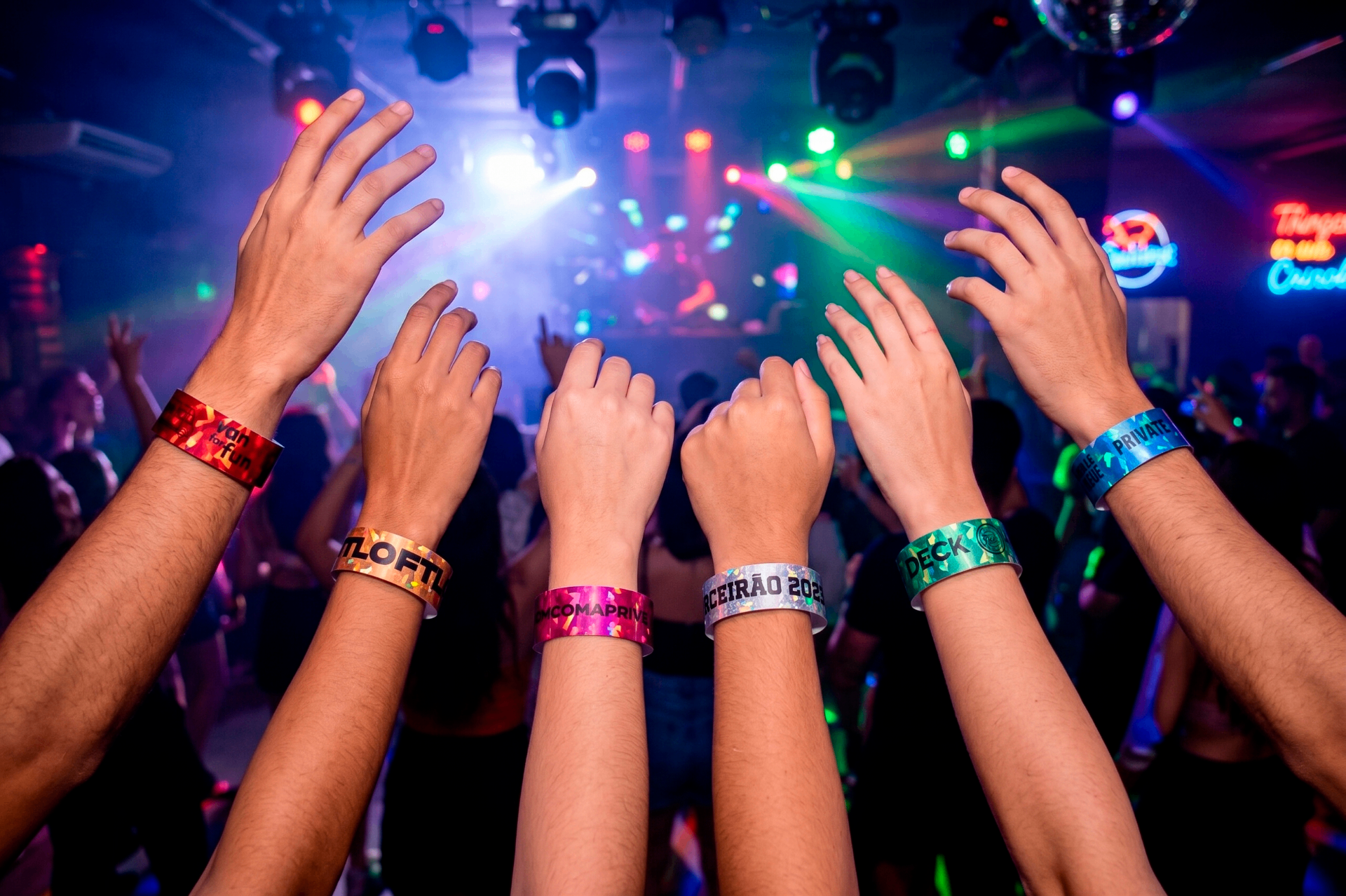 Pessoas em balada exibindo pulseiras holográficas